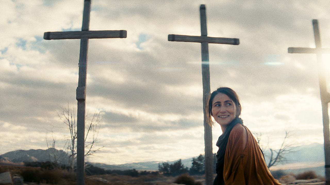 A woman passes three crosses
